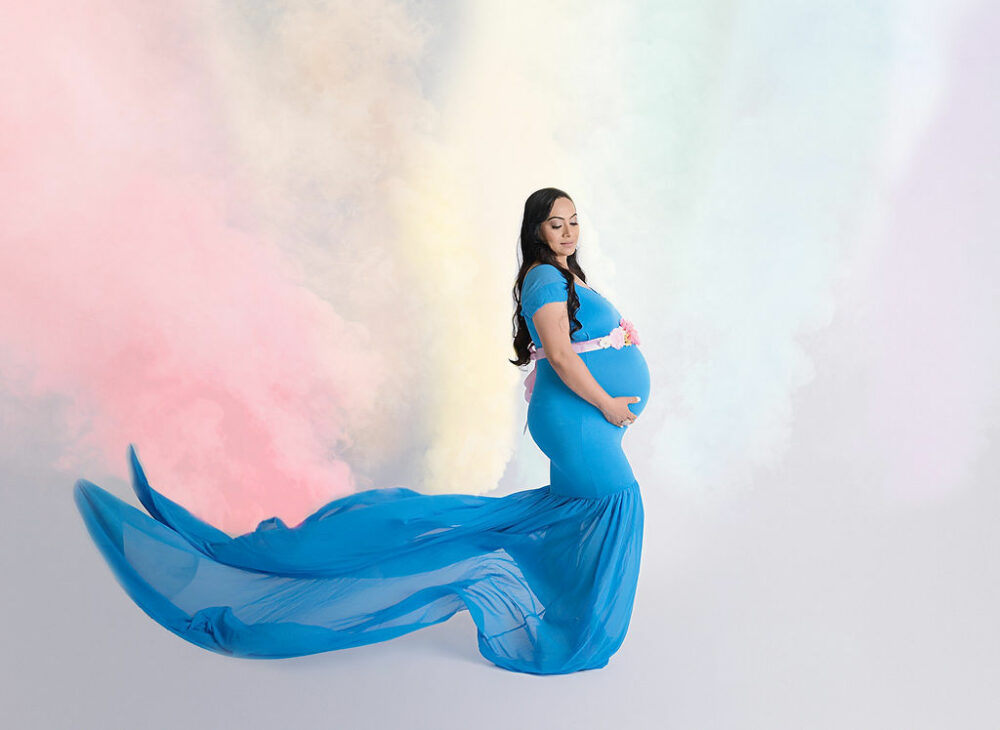 Side-profile of a woman, holding her belly and looking down for her unique maternity portraits, take it in studio in Eastampton, New Jersey.