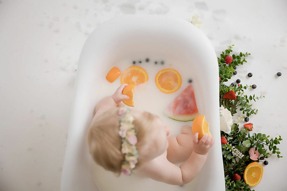 Toddler girl sitting in bathtub photography prop for her first birthday photoshoot for her fruit medley first birthday session in Southampton, New Jersey.