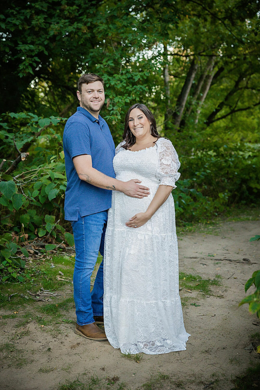 Man and woman standing next to each other both holding her belly for her couple maternity poses ticket for her outdoor maternity session in Freehold, New Jersey.
