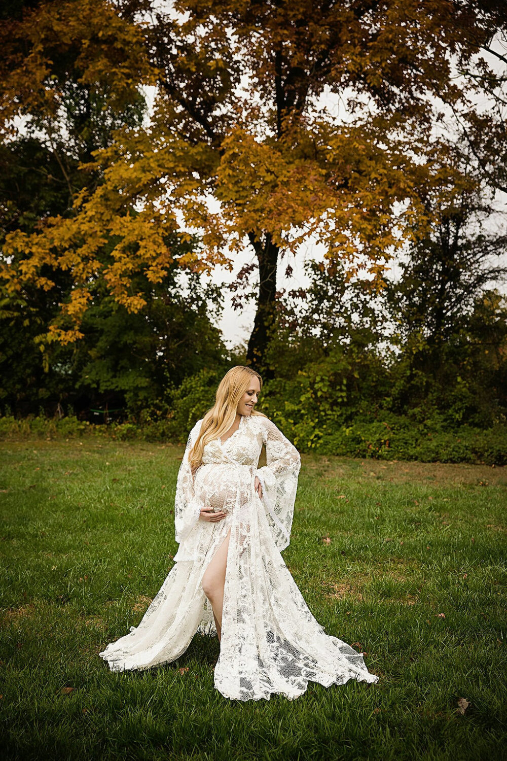 Woman standing outside wearing lace maternity dress doing classic maternity poses for her maternity photo shoot taken in Warren, New Jersey.
