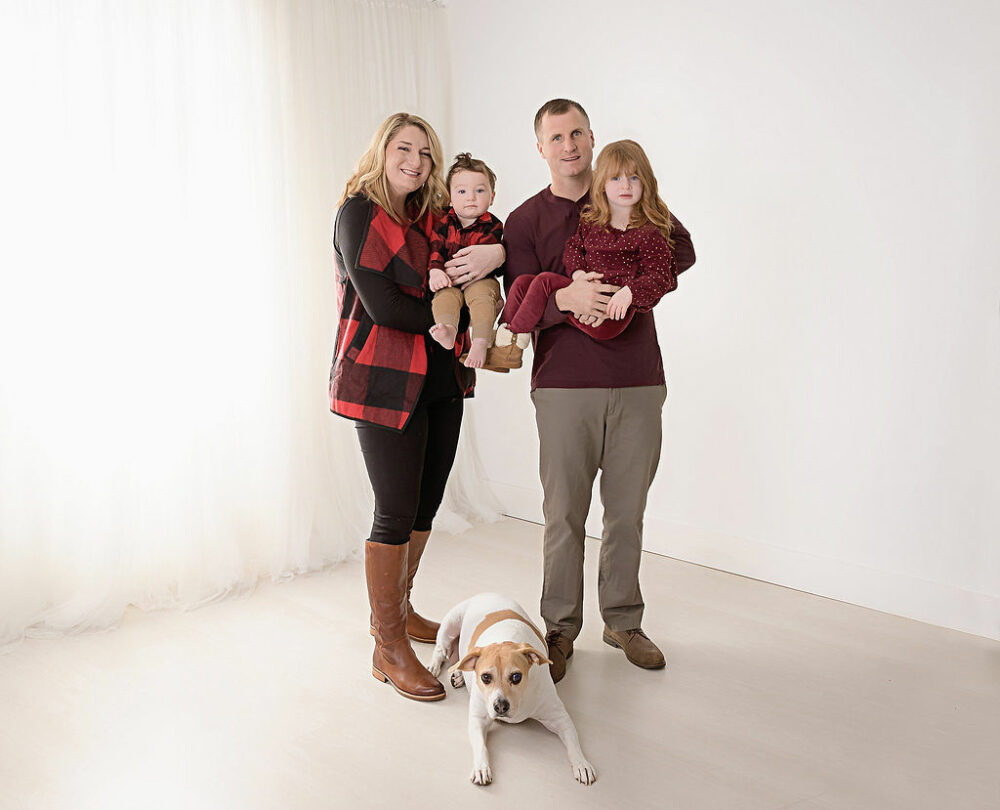 Family portrait of a mom and dad each carrying a child with their family dog in between them taken for a wild one fresh birthday session, taken in studio in Warren, New Jersey.