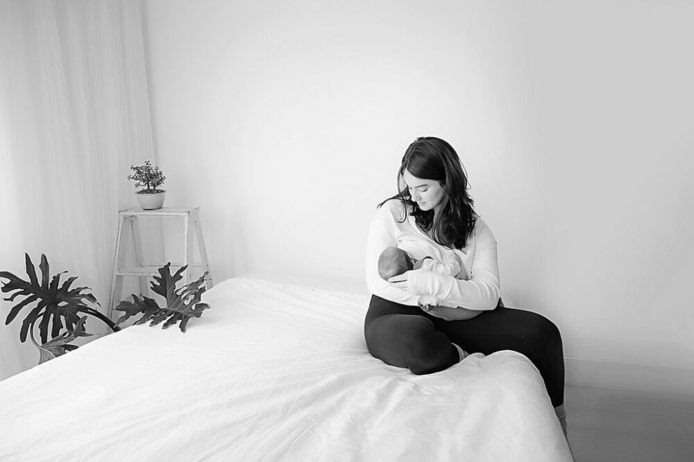 Black and white photo of a mother breast-feeding her infant daughter during their professional BoHo mommy and me session taken in freehold, New Jersey.