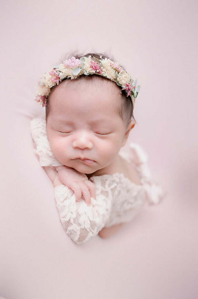 A close-up of a newborn girl sleeping on tummy with her hands rested on her arms for her infant photographers near me in Burlington, New Jersey.