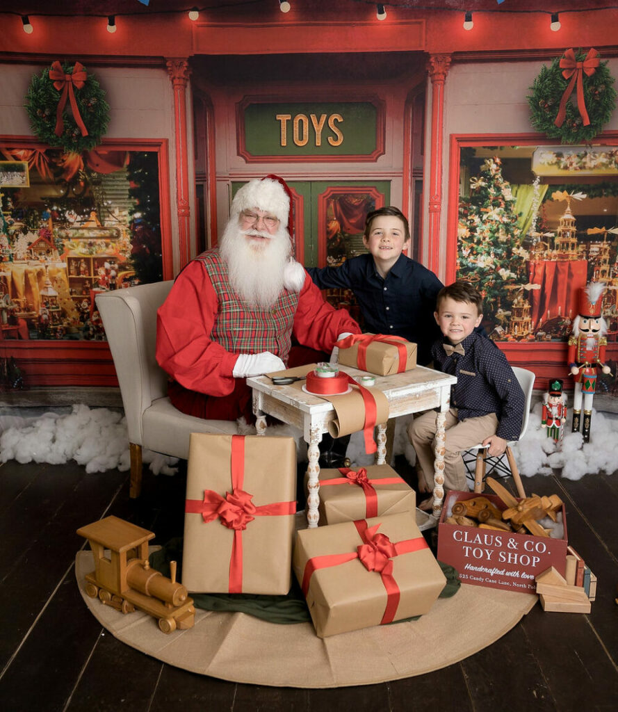 Studio photography of two boys and santa wrapping presents in professional studio for their photography session in Warren, New Jersey.