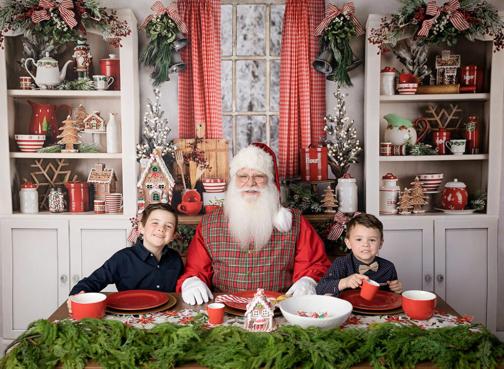 A man dressed up in holiday clothing with large beard and hat sitting next to two brothers, drinking Coco on photography set for Santa mini sessions in Eastampton, New Jersey.