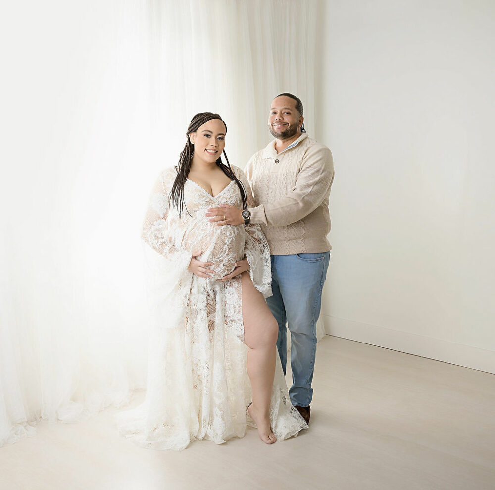 Man and woman posing and holding her belly for their in-studio maternity and newborn session in Burlington, New JErsey.