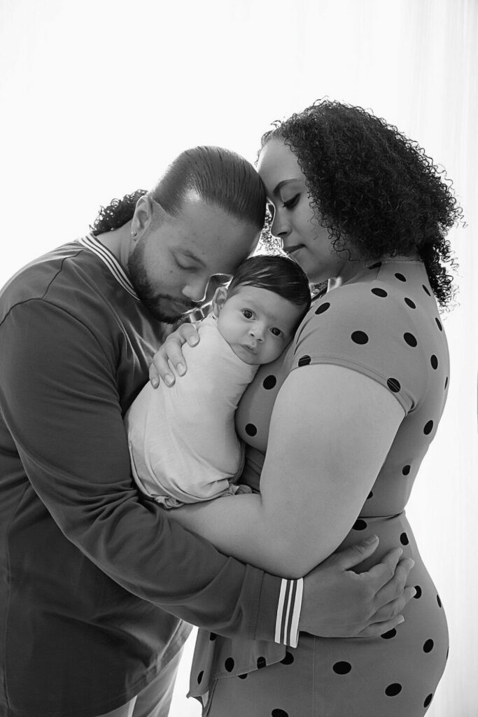 Black-and-white portrait of a man and a woman embracing their infant in their arms for their maternity photography session in Wrightstown, New Jersey.