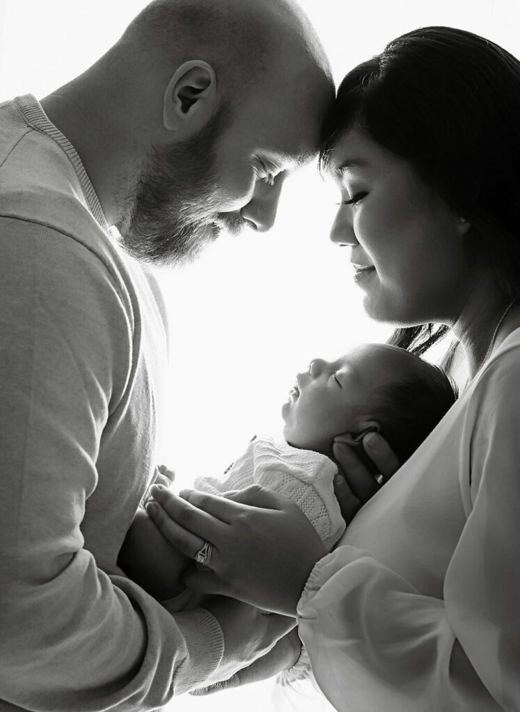 Family portrait of new parents holding their newborn son in between them for their professional in-studio session in Vincentown, New Jersey.