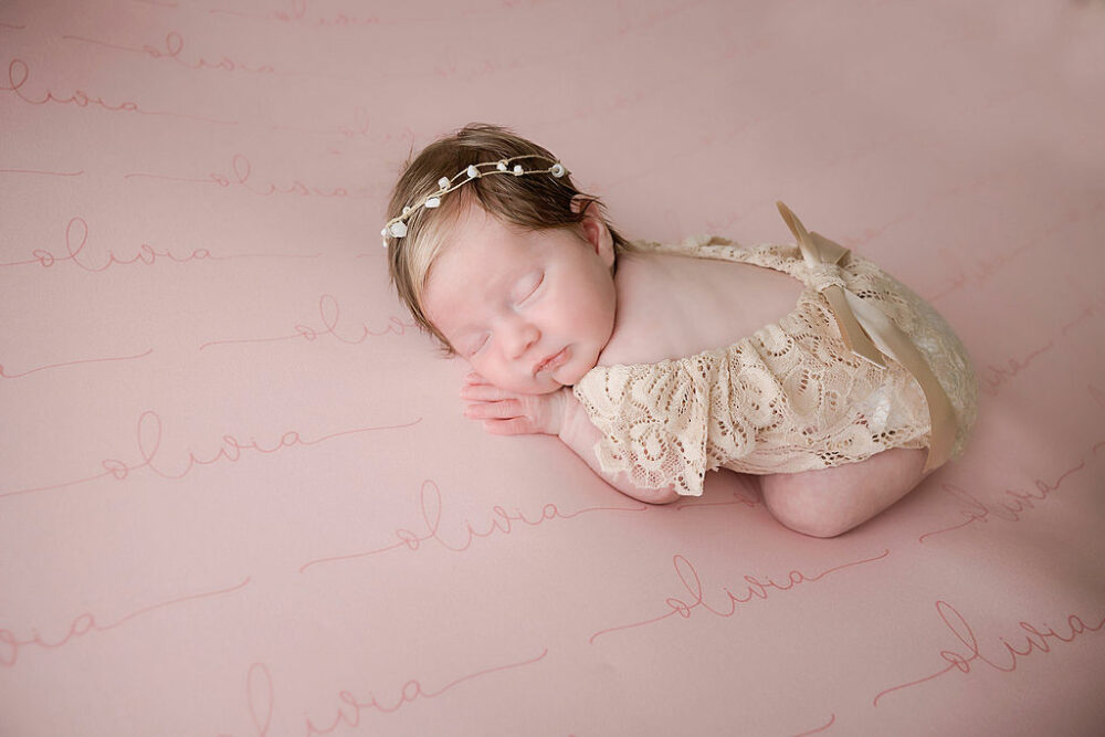 A Newborn laying on her tummy, sleeping on a blanket, wearing cute outfit and dainty headband for her airy newborn session in Lumberton, New Jersey.