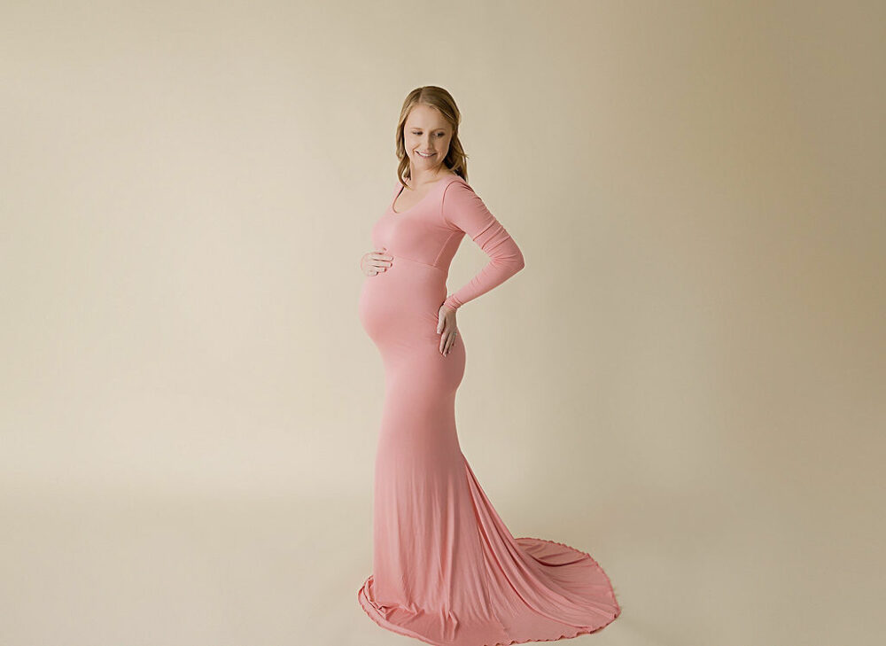 A Maternity portrait of a woman standing and posing wearing a long gown for her airy maternity session in Pemberton, New Jersey.