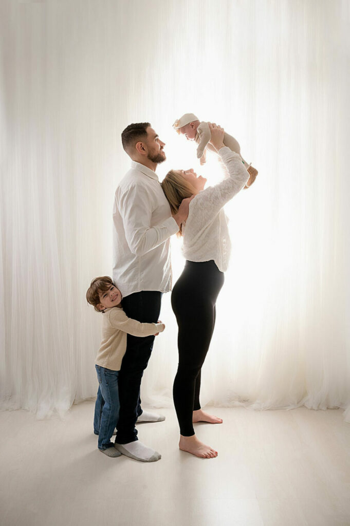 Family photography of a man and a woman posing with her two children taken during their lifestyle in studio family session in Princeton, New Jersey.