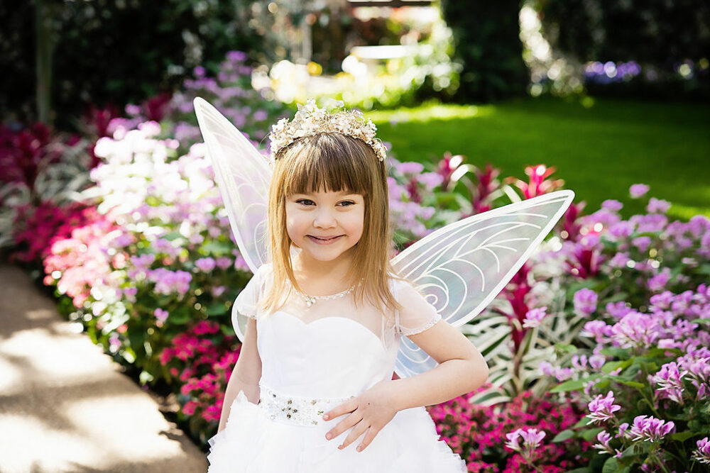 Picture of a girl posing in front of a flower bed, wearing cute outfit for her fairy garden birthday session in Southampton, New Jersey.
