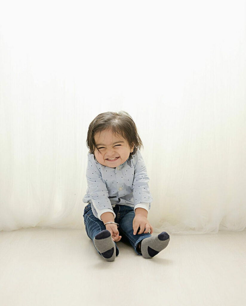 Candid portrait of a girl sitting on the floor and laughing during her professional photography session, taken during her cake, smash photos in Morristown, New Jersey.