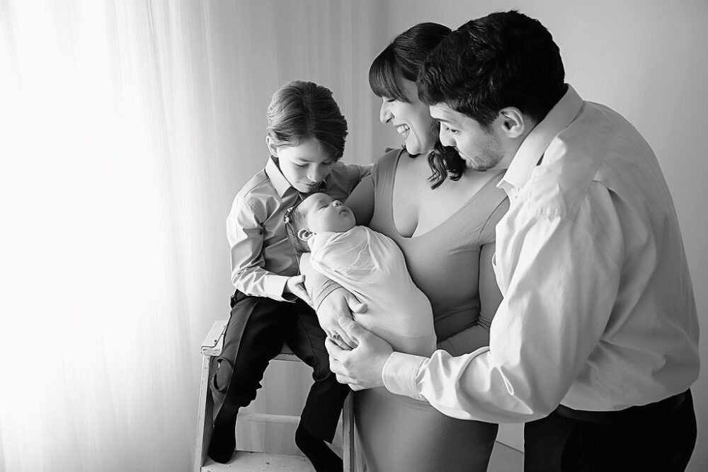 Black and white family portrait of a couple and their two children posing for their family portrait taken during a newborn session in Eastampton, New Jersey.