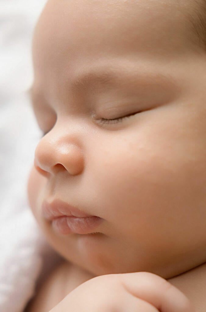 Close up of a infant girl as she sleeps highlighting her little nose lips and eyes during her baby portraits photography session in Tabernacle, New Jersey.
