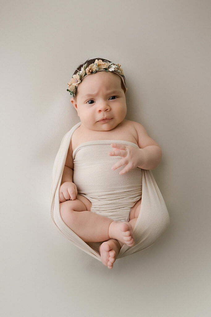 Close up of a infant girl wrapped in swaddle wearing cute headband for her professional baby photography session in Morristown, New Jersey.