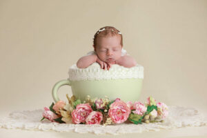 A composite photo of a infant sleeping in a large tea cup adorned with flowers and textured blanket for her inspired newborn session in Wrightstown, New Jersey.