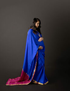 A woman standing and holding her belly, posing for her pregnancy portraits, wearing a sorry for her Indian inspired maternity session in Eastampton, new jersey.