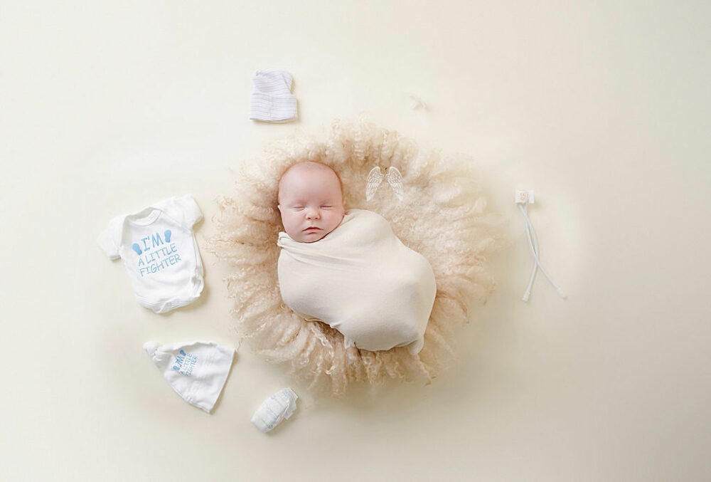 When portrait of a boy sleeping on photography prop textured blanket adorned with a NICU Momentos, swaddled for his twin NICU newborn session in Pemberton, New Jersey.