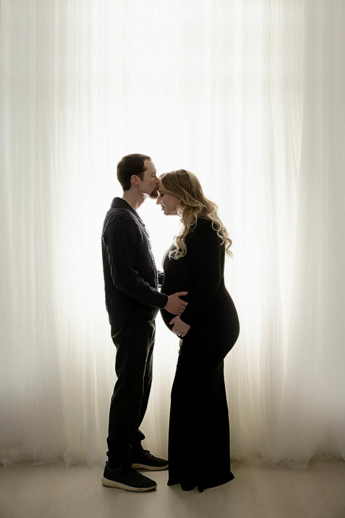 A man and woman facing each other and posing for her pregnancy photos for their belly portraits in Freehold, New Jersey.
