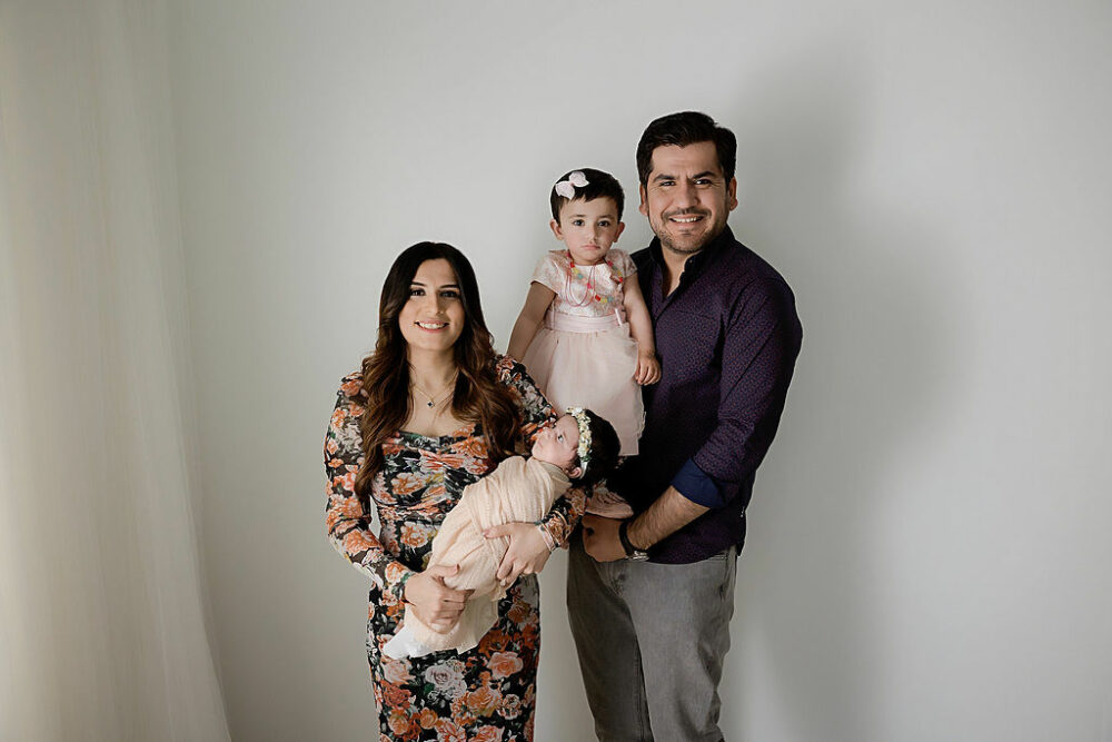 Family portrait of a couple posing with their two daughters for a in-studio floral newborn session in Westampton, New Jersey.