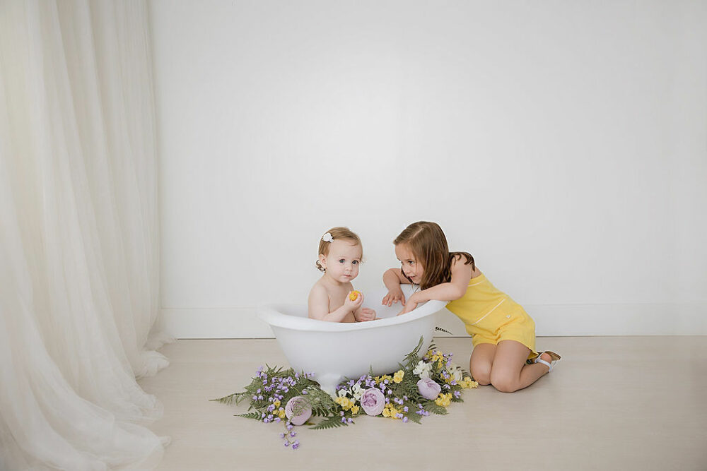 A picture of two sisters playing together during a rainbow pastel first birthday session in Eastampton, New Jersey.