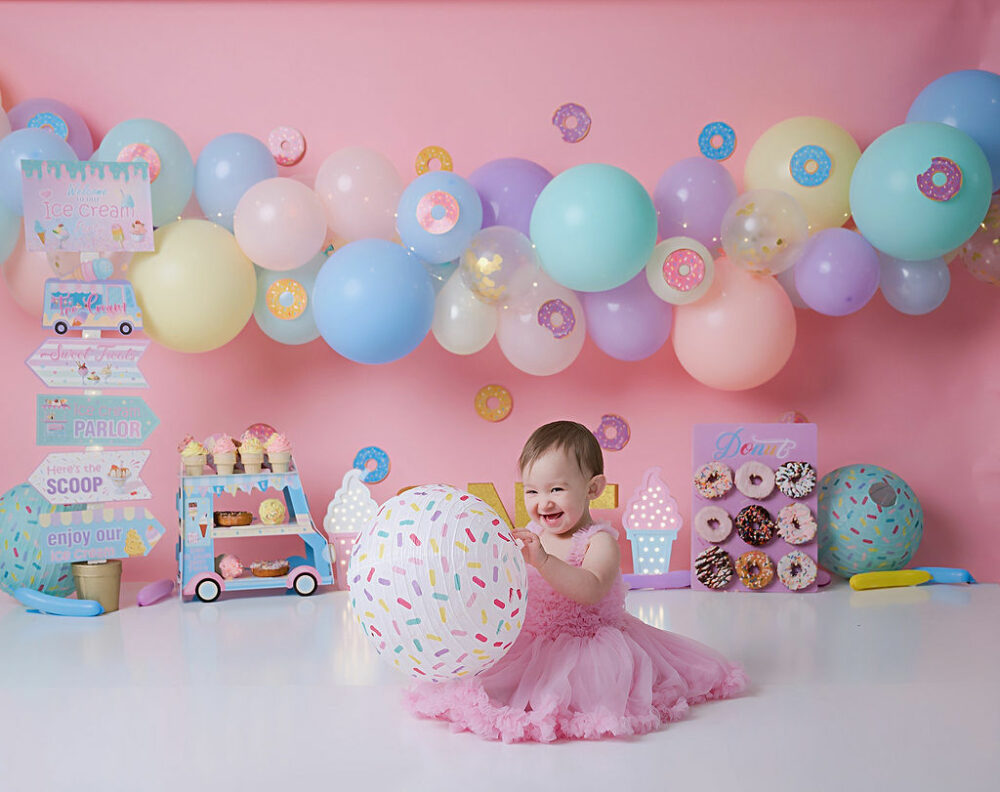 Portrait photography of a one-year-old girl smiling and having fun during her cake smash birthday photoshoot in Medford, New Jersey.