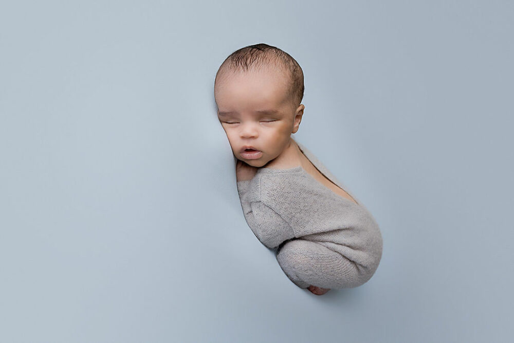 A infant sleeping during his dreamy in studio newborn session wearing cute outfit for his infant photos in Moorestown, New Jersey.