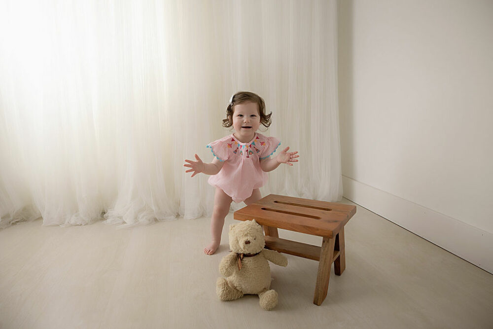 A portrait of a girl, smiling and walking during her pink mini mouse first birthday session in Eastampton, New Jersey.