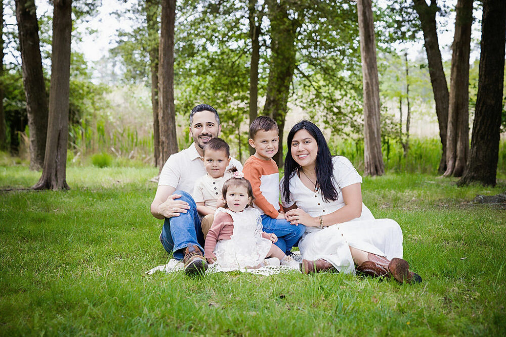Family photography of a couple and their two sons and daughter posing, and sitting on grass for their Spring outdoor family session in medford, New Jersey.