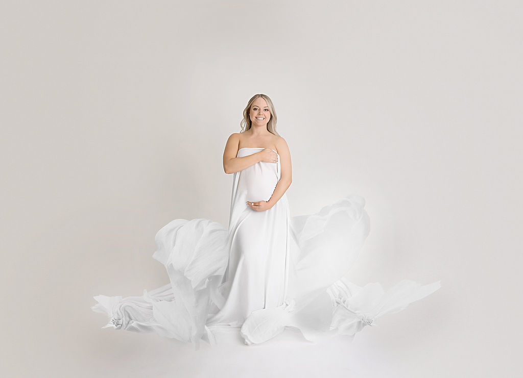 A woman wearing a long dress and posing for her maternity pictures in professional studio in Mount Holly, New Jersey.