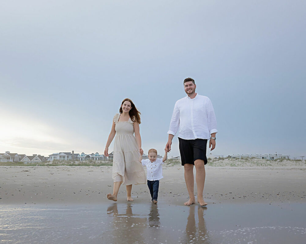 A lifestyle photo of a family walking on the beach for their creative portrait photography session in Cape May, New Jersey.