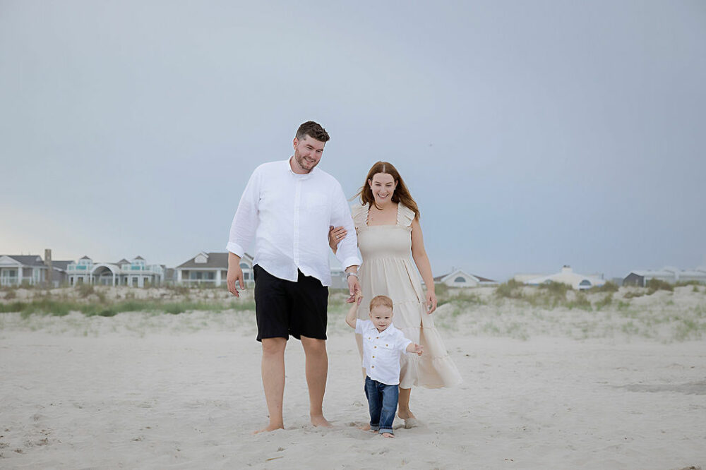 A beautiful family portrait of a woman wearing dress while her son and husband wear a white T-shirt and denim for their beach family session in Atlantic City, New Jersey.