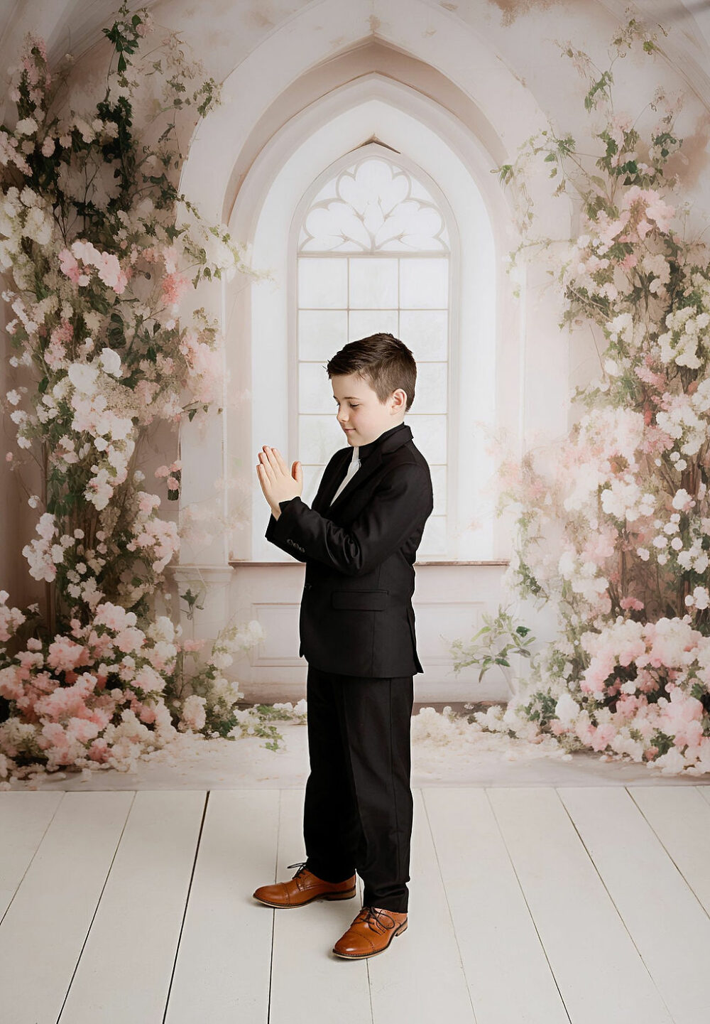 A cute portrait of a boy wearing suit standing in professional studio for his first communion photography session in Eastampton, New Jersey.