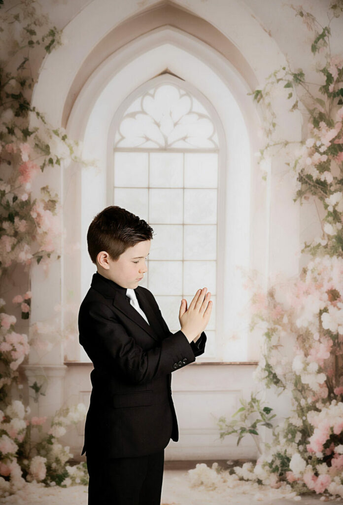 A close-up of a boy standing to the side posing with prayer hands for his communion mini session in Westampton, New Jersey.