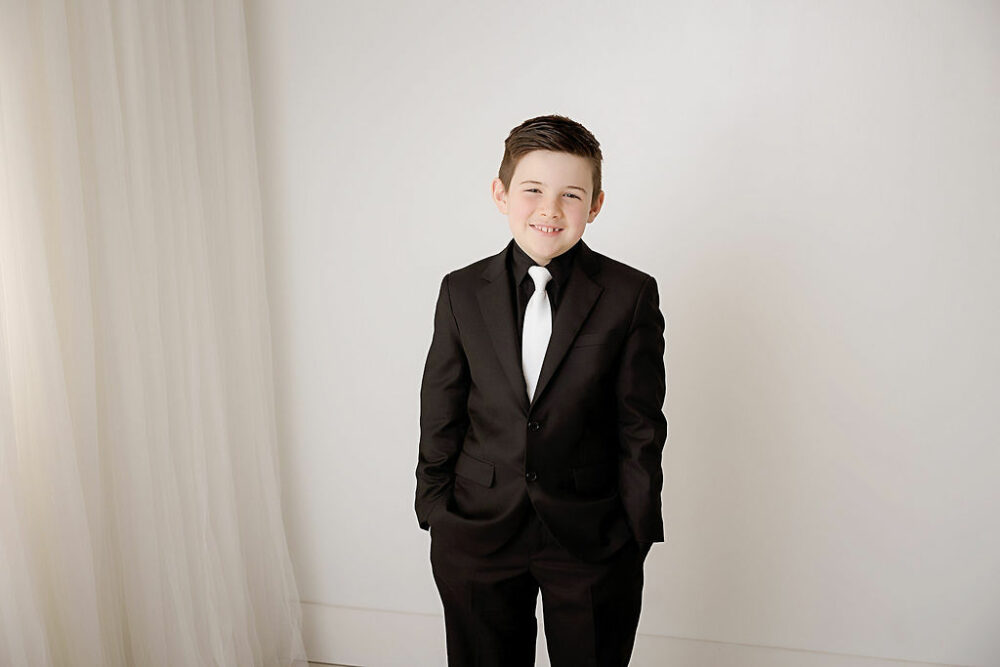 A close-up of a boy wearing suit and smiling for his professional photo shoot for his communion photos in Morristown, New Jersey