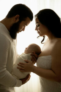 A close-up photo of a man and woman holding their newborn son between them as they look down on him for a classy newborn session in Pemberton, New Jersey.