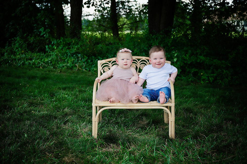 A sibling portrait of fraternal twins sitting on tiny bench smiling for their country cake smash session in Eastampton, New Jersey.
