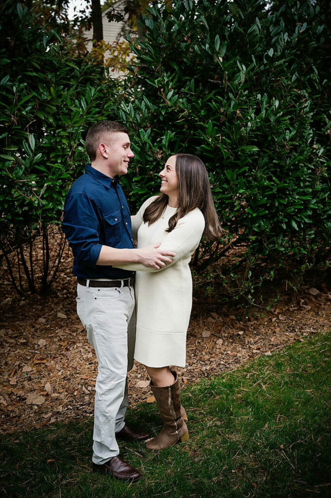 A couple family portrait of a man and woman laughing and standing outdoors looking and smiling at each other during their fall family sessions in Southampton, New Jersey.