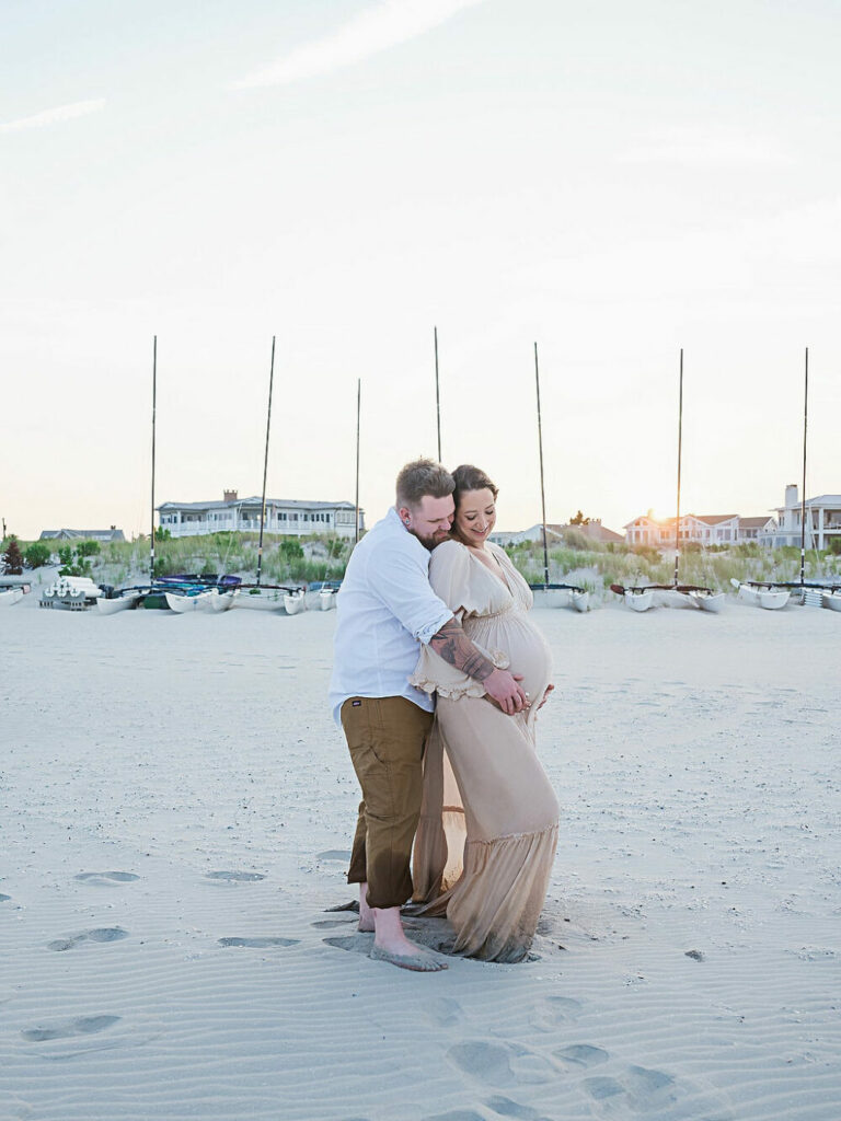 A beautiful couple portrait of a man and women embracing each other as a hold her belly during her beach maternity session and Ocean city, New Jersey.