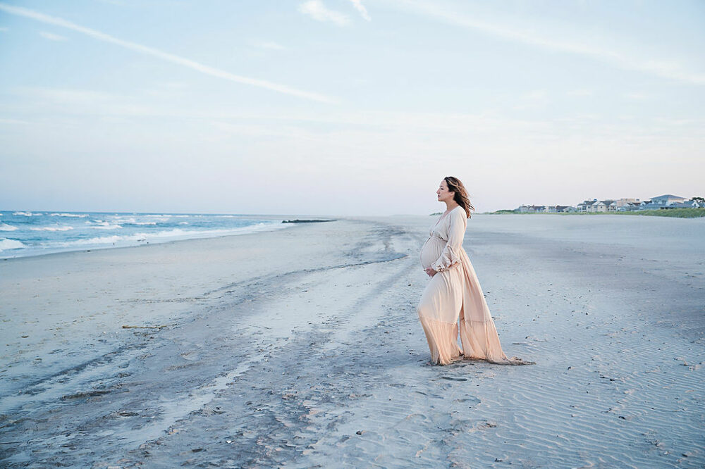 A beautiful photo of a woman standing in facing the ocean that she stand on the shore for her professional maternity photography session in Atlantic City, New Jersey.